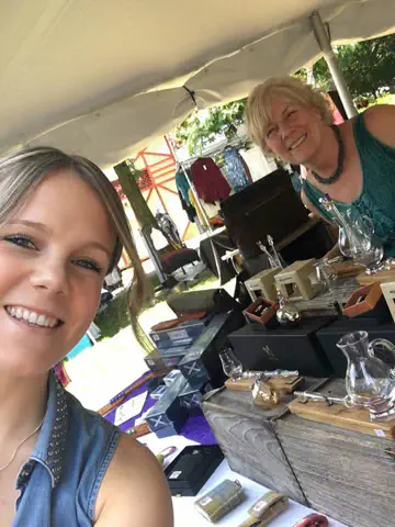 Two people at a Scottish Creations outdoor stall displaying glassware and gifts.